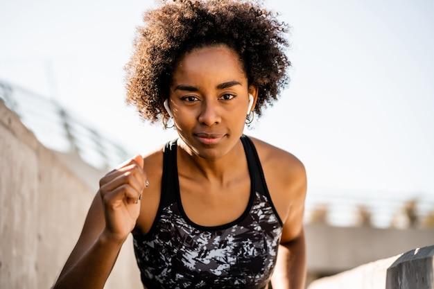Porträt der Afroathletenfrau, die draußen Sport läuft und tut. Sport und gesunder Lebensstil.