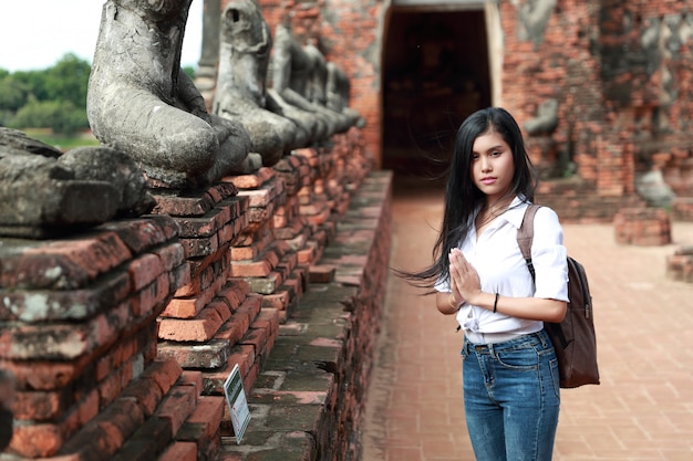 Porträt der asiatischen Frau des schönen Reisenden, die Respekt im alten Tempel zahlt