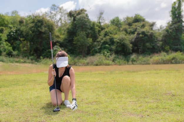 Porträt der asiatischen Golfspielerin, die Golfholz im Country Club hältGlückliches FrauenkonzeptGolf auf Pin setzen