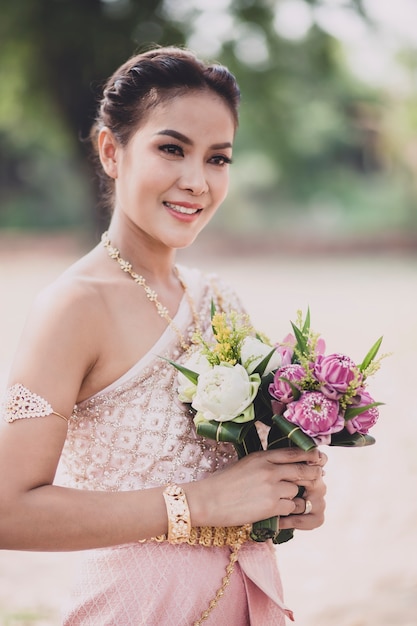 Porträt der asiatischen jüngeren Frau, die thailändische traditionelle Kleidung trägt