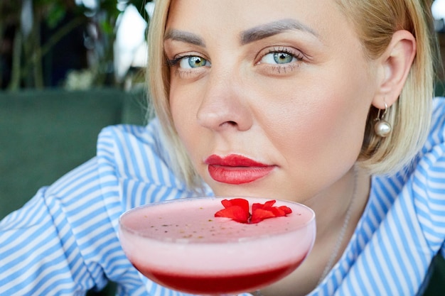 Porträt der attraktiven jungen Frau, die Cocktail im Innencafé trinkt Schöne blonde Frau, die an der Bar sich entspannt und einen Cocktail trinkt