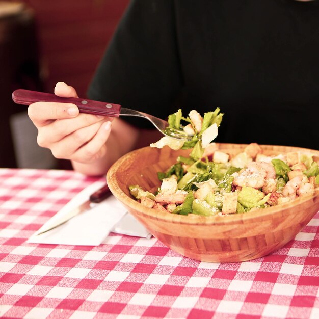 Porträt der attraktiven kaukasischen lächelnden Frau, die Salatfokus auf Hand und Gabel isst