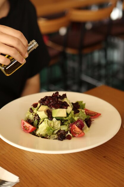 Porträt der attraktiven kaukasischen lächelnden Frau, die Salatfokus auf Hand und Gabel isst