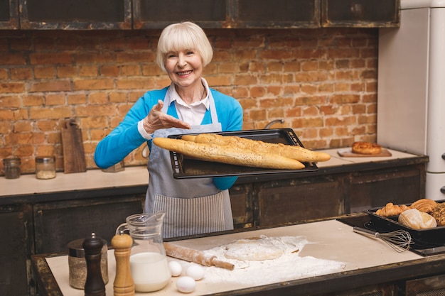 Porträt der attraktiven lächelnden glücklichen älteren älteren Frau kocht auf Küche. Großmutter macht leckeres Backen.