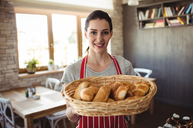 Porträt der Bäckerin, die einen Korb der Brotlaibe hält