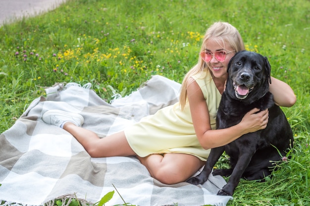 Porträt der blonden Frau in der rosa Brille und im Hund