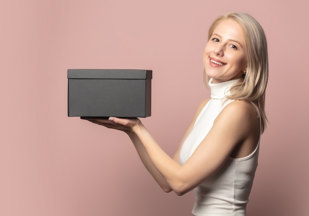 Porträt der Blondine in der Spitze mit schwarzer Geschenkbox auf rosa