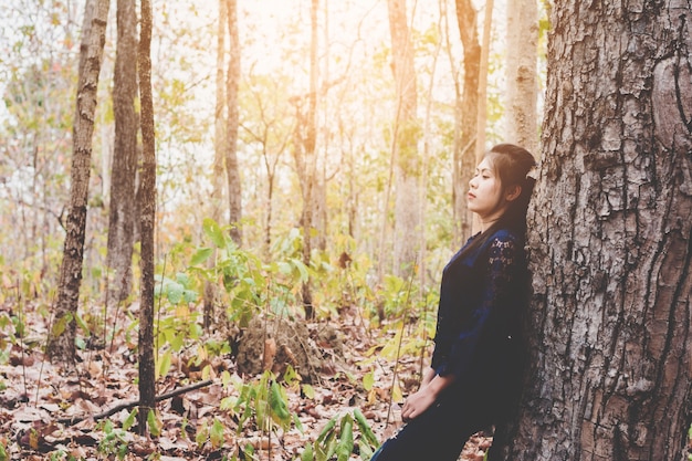 Porträt der depressiven und hoffnungslosen jungen Frau beruhigen sich im Wald an der Landschaft