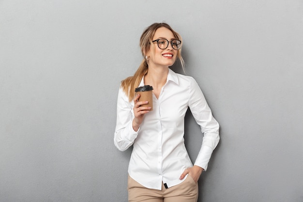 Porträt der europäischen Geschäftsfrau, die Gläser trägt, die Kaffee vom Pappbecher im Büro trinken, lokalisiert