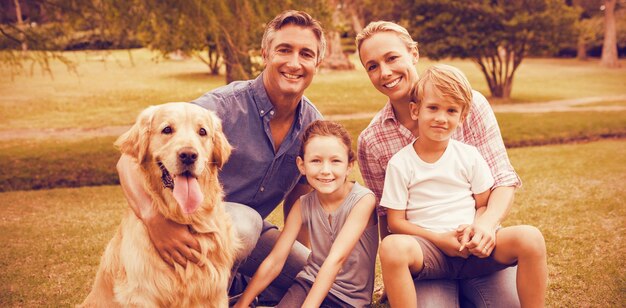 Foto porträt der familie, die an einem sonnigen tag mit hund im park genießt