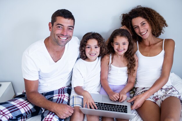 Porträt der Familie, die zusammen Laptop auf Bett verwendet