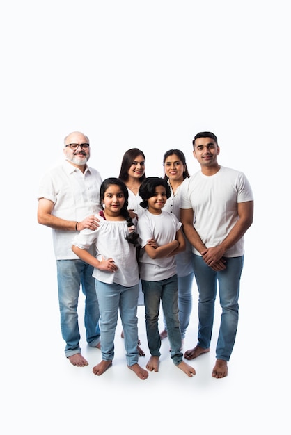 Porträt der Familie Indn mit Großeltern, Eltern und Kindern gegen weiße Wand in weißen Tüchern