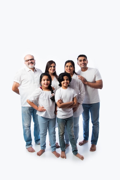 Porträt der Familie Indn mit Großeltern, Eltern und Kindern gegen weiße Wand in weißen Tüchern