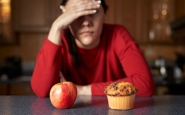 Foto porträt der frau, die zwischen junk food und natürlichem gesundem bio-lebensmittel wählt