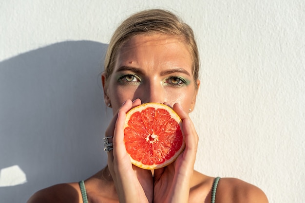 Porträt der Frau im Badeanzug mit einer Grapefruit.