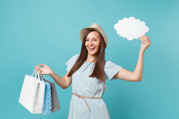 Porträt der Frau im Sommerkleid, Strohhut, der Pakettaschen mit Einkäufen nach dem Einkaufen hält, leeres leeres Sagen Sie Wolke, Sprechblasenkarte lokalisiert auf blauem Pastellhintergrund. Platzwerbung kopieren