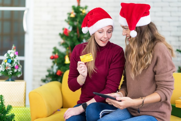 Porträt der Frau und des Freundes, die eine leere Kreditkarte in den Weihnachtsferien-, Weihnachts- und Neujahrseinkäufen im Internet zeigen, Zahlung per Kreditkarte.