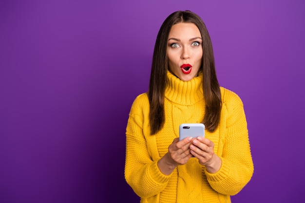 Porträt der fröhlichen positiven netten hübschen niedlichen Frau, die Telefon hält, das nahe dem leeren Raum mit den Lippen pomadiert steht.