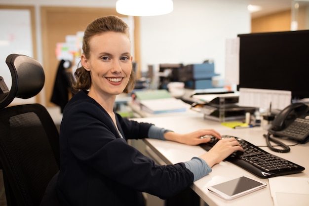 Foto porträt der geschäftsfrau, die auf tastatur im büro tippt