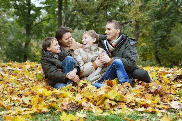 Porträt der glücklichen Familie, die im Herbstpark sich entspannt