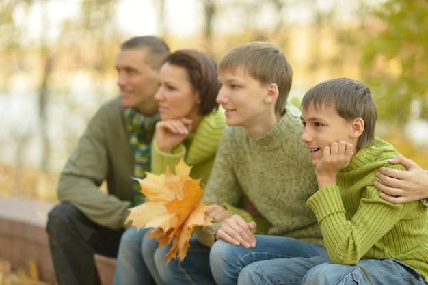 Porträt der glücklichen Familie, die im Herbstpark sich entspannt