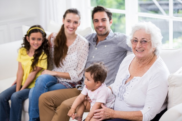 Porträt der glücklichen Familie mit Baby beim Sitzen auf Sofa