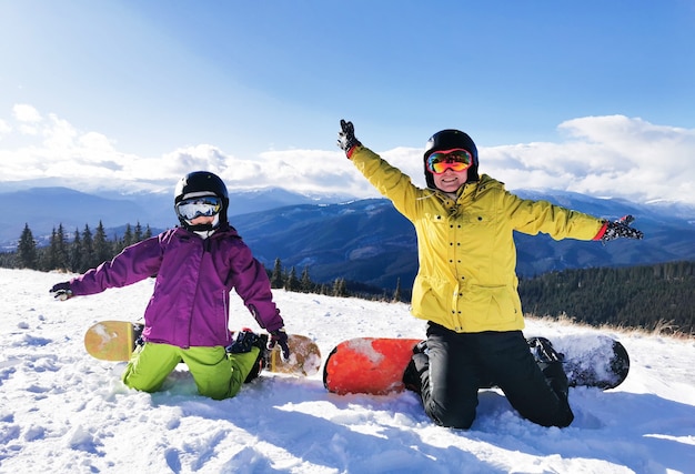 Porträt der glücklichen Familie mit Snowboards, die Kamera auf blauem Hintergrund betrachten