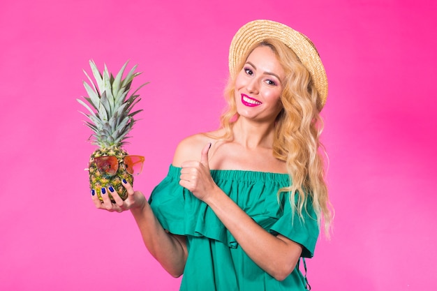 Porträt der glücklichen Frau und der Ananas über rosa Hintergrund. Sommer, Ernährung und gesunder Lebensstil