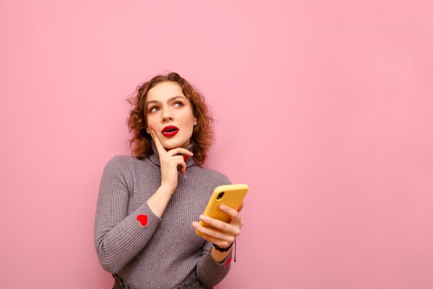 Porträt der glücklichen hübschen Dame im grauen Pullover und im lockigen Haar