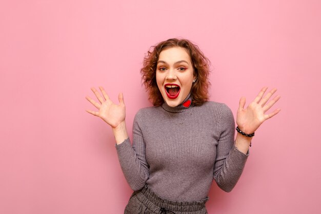 Porträt der glücklichen hübschen Dame im grauen Pullover und im lockigen Haar