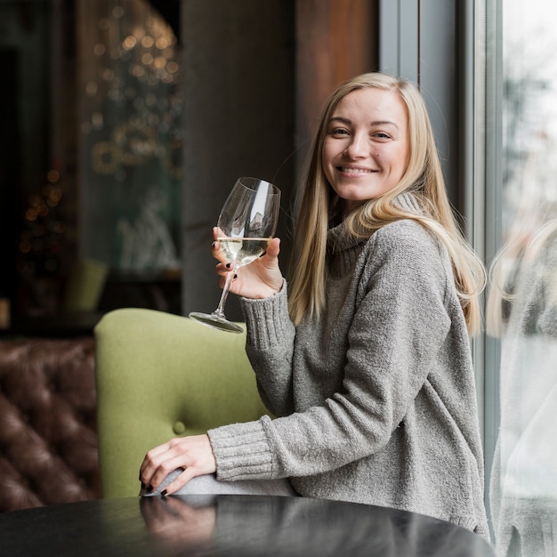 Porträt der glücklichen jungen Frau, die ein Glas Wein hat