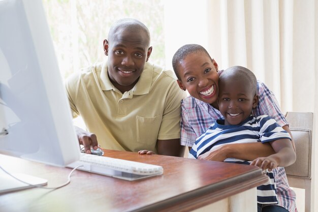 Porträt der glücklichen lächelnden Familie unter Verwendung des Computers