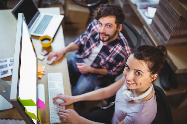 Porträt der glücklichen Mitarbeiter, die am Computertisch arbeiten