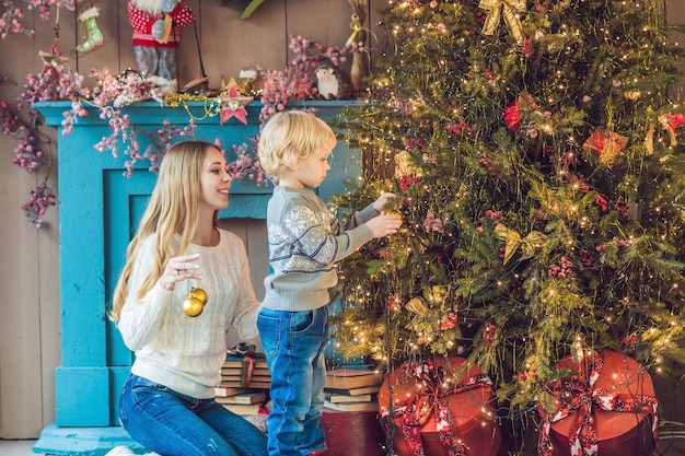 Porträt der glücklichen Mutter und des entzückenden Jungen, der Weihnachten feiert. Kleinkind mit Mutter