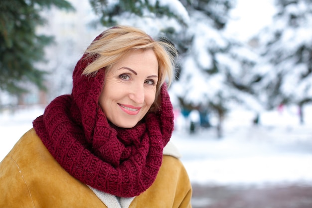 Porträt der glücklichen reifen Frau im verschneiten Park im Winterurlaub