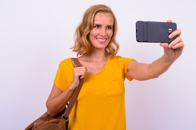 Porträt der glücklichen schönen blonden Touristenfrau mit Rucksack, der selfie nimmt