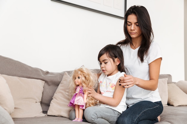 Porträt der herrlichen Familienmutter und des Kindes, die Zeit zusammen verbringen, auf Sofa im Wohnzimmer sitzend