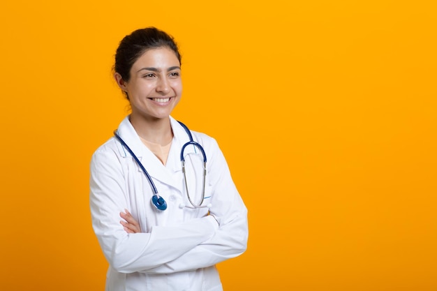 Porträt der indischen Doktorfrau im weißen medizinischen Kittel lokalisiert auf gelbem Hintergrund