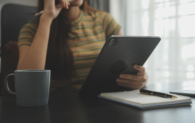 Porträt der jungen asiatischen Freiberuflerin arbeitet an ihrem Job auf einem Computer-Tablet in einem modernen Büro