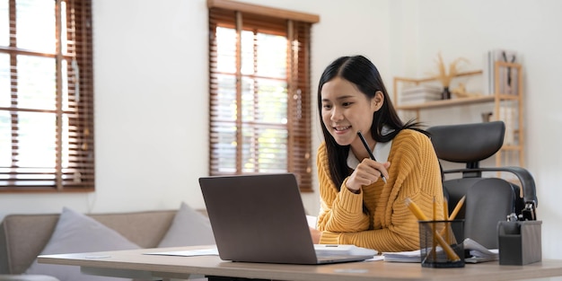 Porträt der jungen asiatischen Freiberuflerin arbeitet an ihrem Job auf einem Computer-Tablet in einem modernen Zuhause