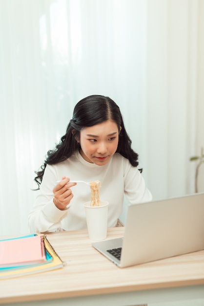 Porträt der jungen asiatischen Freiberuflerin, die mit Laptop an ihrem Haus arbeitet