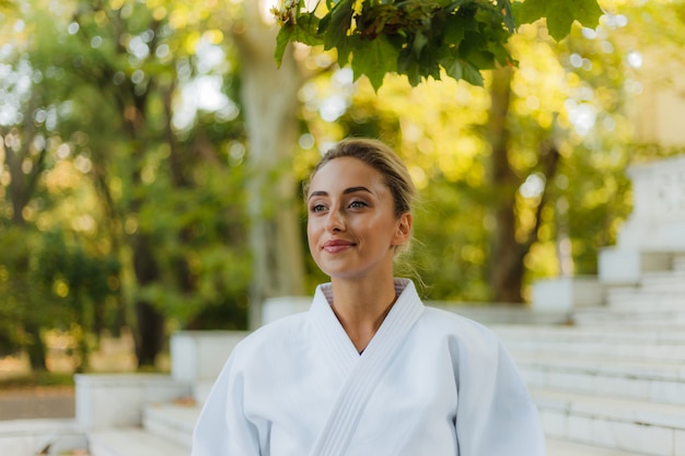 Porträt der jungen attraktiven Frau im weißen Kimono. Sportfrau im Freien. Kampfkunst