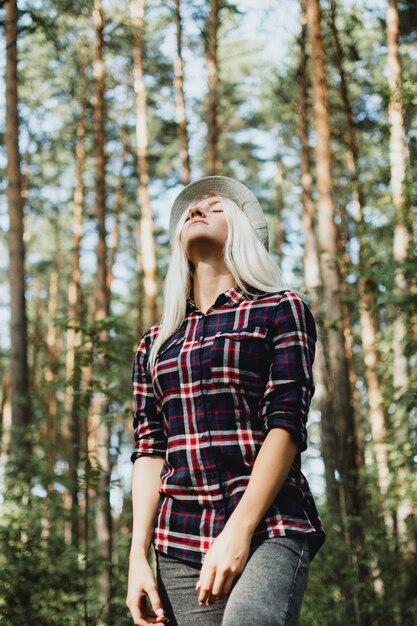 Porträt der jungen erwachsenen Frau im karierten Hemd, das im Wald geht, selektiver Fokus