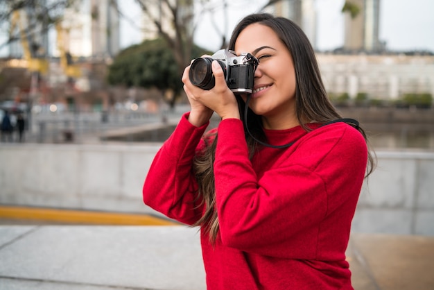 Porträt der jungen Fotografenfrau unter Verwendung einer professionellen Digitalkamera im Freien. Fotografie-Konzept