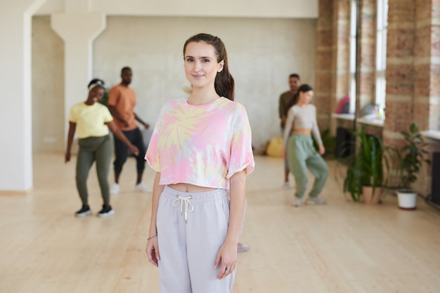 Porträt der jungen Frau beim Tanzen mit anderen Leuten im Tanzstudio