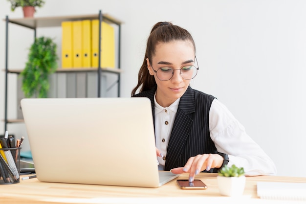 Foto porträt der jungen frau, die am laptop arbeitet