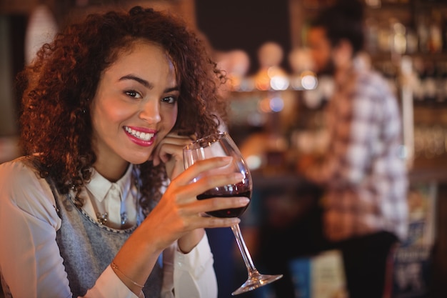 Porträt der jungen Frau, die Rotwein hat