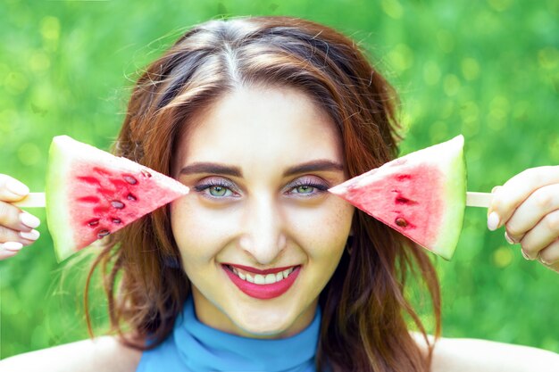 Porträt der jungen Frau, die zwei Stücke Wassermelone hält.