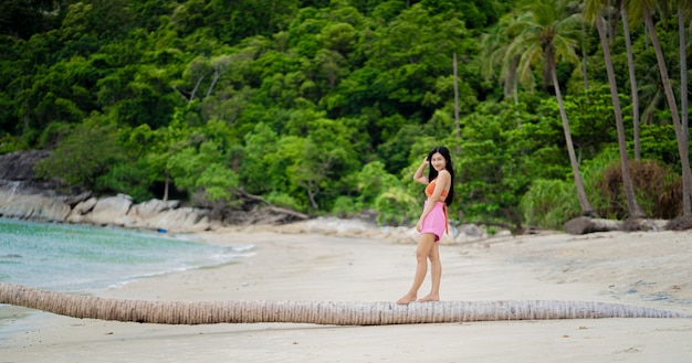 Foto porträt der jungen frau im orangefarbenen bikini am tropischen strand