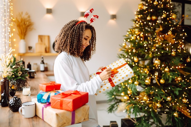 Porträt der jungen Frau in Weihnachtsmann-Hut mit Geschenk am Weihnachtsbaum Weihnachten Neujahr